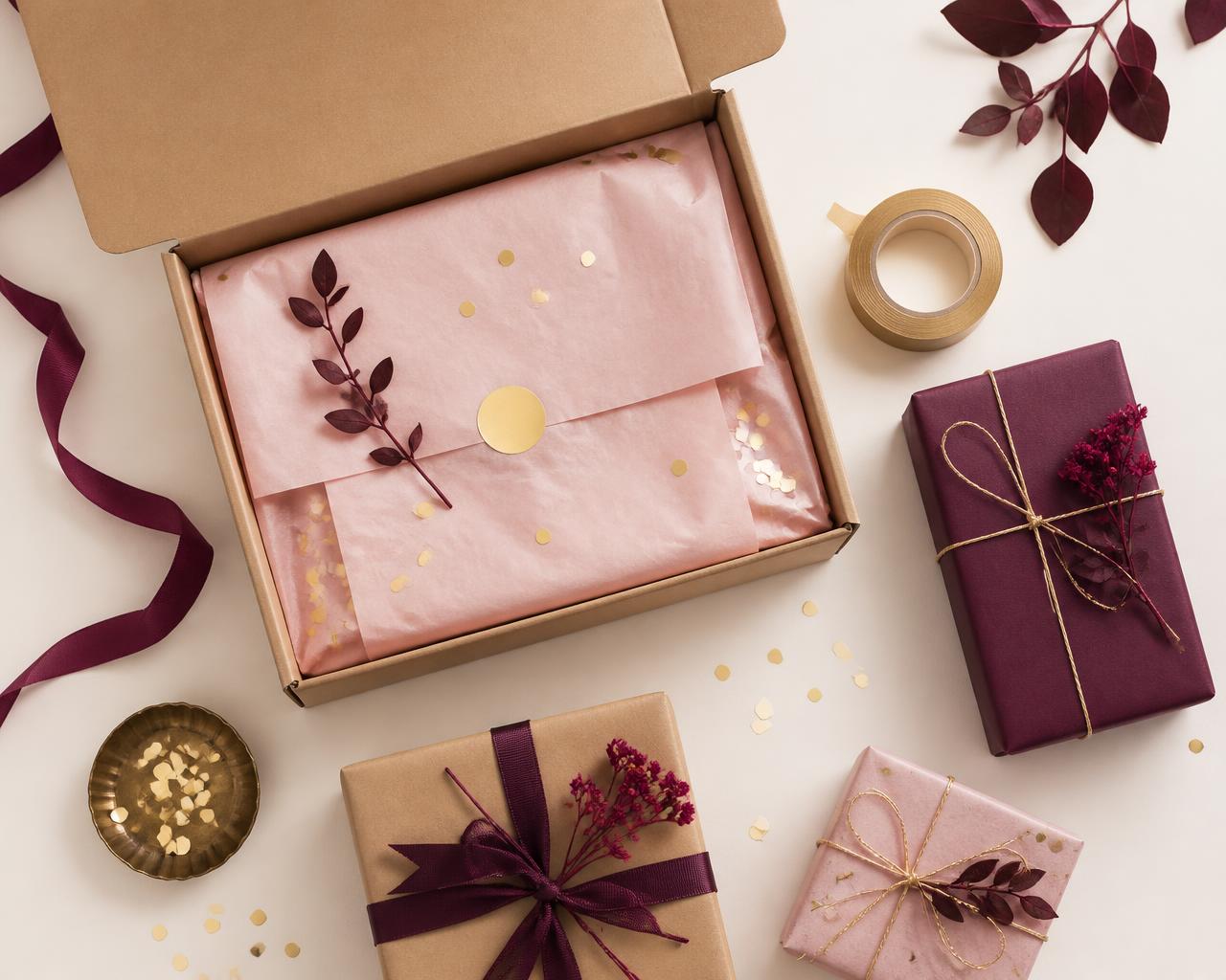 An open kraft Pretty Packed Box with blush tissue paper, gold confetti and wrapped parcels